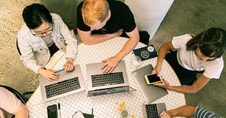 Agency team collaborating around a table with laptops